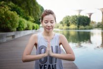 Junge sportliche asiatische Frau macht Yoga am Pier — Stockfoto