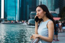 Junge Asiatin fährt mit Smartphone gegen Hochhäuser — Stockfoto