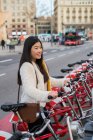 Jovem chinesa alugando uma bicicleta em Barcelona — Fotografia de Stock