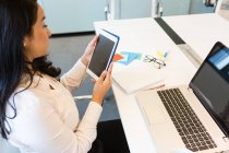 Mujer joven usando tableta digital en el escritorio en la oficina moderna - foto de stock