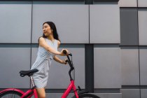 Молода азіатка, що йде з велосипедом — стокове фото