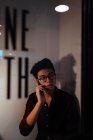Азиатский мужчина в очках на говорящем мобильном телефоне в офисе — стоковое фото