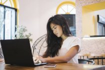 Молода азіатська жінка працює на ноутбуці в творчому сучасному офісі — стокове фото