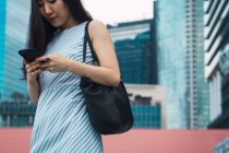 Молода азіатська жінка використовує смартфон на вулиці — стокове фото