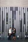 Young asian couple standing beside building wall — Stock Photo