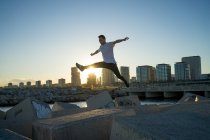 Jeune asiatique homme saut sur blocs au coucher du soleil — Photo de stock