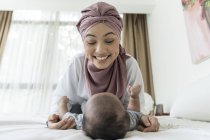 Asian muslim mother playing with baby on bed — Stock Photo
