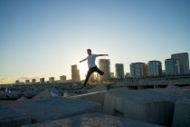 Jovem asiático homem jumping no blocos no por do sol — Fotografia de Stock