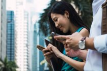 Pareja de negocios adultos jóvenes utilizando teléfonos inteligentes al aire libre - foto de stock