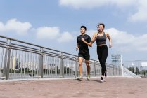 Счастливая азиатская спортивная пара бегает в городе вместе — стоковое фото
