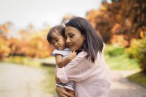 Cute asian mother and daughter hugging in park — Stock Photo