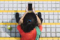 Young asian sporty woman using smartphone on stairs, elevated view — Stock Photo