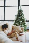 Asiatique famille célébrant Noël vacances, garçon assis sur canapé avec téléphone mobile — Photo de stock