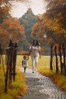 Cute asian mother and daughter walking on path in park — Stock Photo
