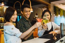 Giovani amici asiatici tifo in confortevole bar — Foto stock