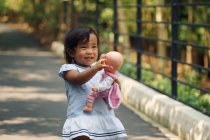 Lindo asiático chica jugando con muñeca en parque - foto de stock