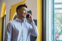 Junger asiatischer Mann mit Smart im kreativen modernen Büro — Stockfoto