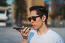 Cool young asian man using smartphone outdoors — Stock Photo