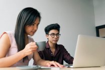 Young asian successful business couple using laptop in modern office — Stock Photo