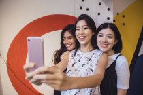 Jóvenes asiático mujeres tomando selfie en creativo moderno oficina - foto de stock