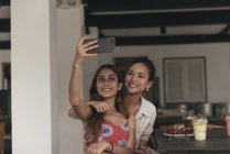 Two young beautiful asian women taking selfie in cafe — Stock Photo