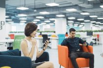 Молодий азіатський бізнес, використовуючи смартфони в сучасному офісі — стокове фото