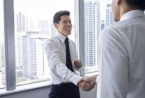 Gutaussehende asiatische Geschäftsleute schütteln Hände im Büro — Stockfoto