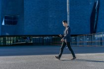 Junger asiatischer Mann läuft mit Smartphone auf Straße — Stockfoto