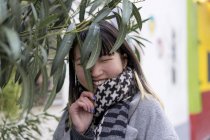 Молодий привабливий випадковий азіатський посміхається біля рослини — стокове фото