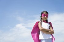 Little cute girl dressed like superhero under blue sky — Stock Photo