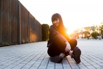 Junge hübsche asiatische Frau sitzt und posiert vor der Kamera bei Sonnenuntergang — Stockfoto