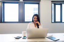 Jovem mulher trabalhando em seu laptop no escritório moderno — Fotografia de Stock