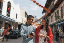 Молода азіатська пара проводить час разом у місті та використовує смартфон — стокове фото