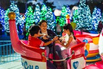 Щасливі азіатські брати і сестри проводять час разом у парку розваг на Різдво — стокове фото