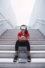 Молода азіатська спортивна жінка використовує навушники і розумний на сходах — стокове фото
