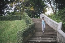 Young asian sporty woman running on stairs in park — Stock Photo