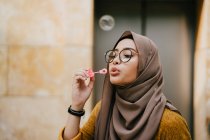 Young asian muslim woman in hijab making bubbles at street — Stock Photo