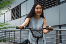 Jeune asiatique femme équitation vélo sur rue — Photo de stock