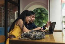 Feliz jovem asiático casal usando laptop no café — Fotografia de Stock