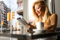 Портрет красивой молодой женщины, использующей свой цифровой планшет в кафе . — стоковое фото