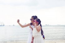 RELEASES Two little sisters spending time together on beach and taking selfie — Stock Photo