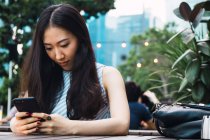 Портрет молодой азиатки с помощью смартфона — стоковое фото