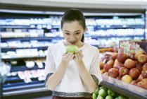 Smiling asian woman holding apple in market — Stock Photo