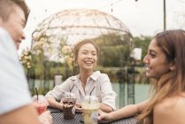 Grupo de amigos en un restaurante, sonriéndose el uno al otro - foto de stock