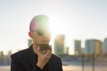 Young asian man in sunglasses using smartphone — Stock Photo