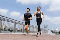Asiática pareja corriendo fuera durante el día - foto de stock