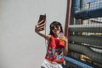 Mujer asiática con auriculares y bebida - foto de stock
