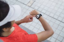 Молода азіатська спортивна жінка перевіряє час на смарт-годиннику — стокове фото