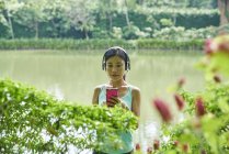 Porträt einer Frau mittleren Alters, die beim Spazierengehen in botanischen Gärten Musik hört — Stockfoto