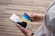 Imagem cortada de mulher segurando cartão de crédito e smartphone — Fotografia de Stock